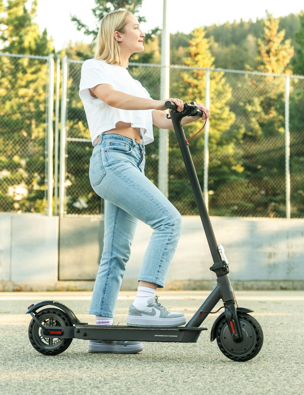 Femme sur une trottinette électrique dans une rue ensoleillée