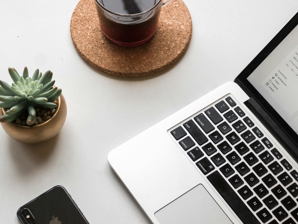 Ordinateur portable et smartphone posés sur un bureau blanc
